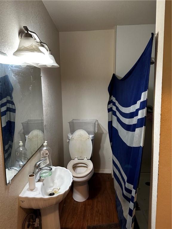 bathroom featuring hardwood / wood-style flooring, a shower with curtain, toilet, and sink