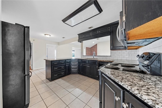 kitchen with sink, decorative backsplash, fridge, light stone counters, and kitchen peninsula