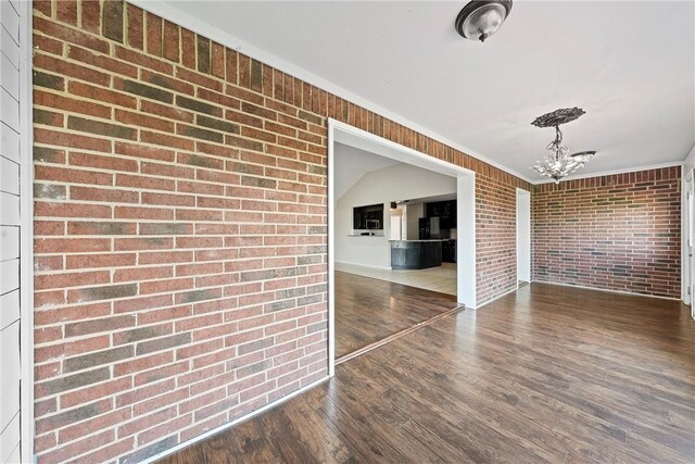 hall featuring dark hardwood / wood-style flooring, brick wall, and a notable chandelier