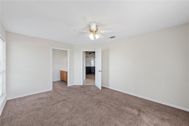 unfurnished bedroom with ceiling fan, light colored carpet, and ensuite bath