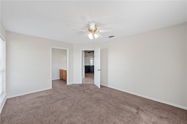 unfurnished bedroom featuring ensuite bathroom, ceiling fan, and light colored carpet