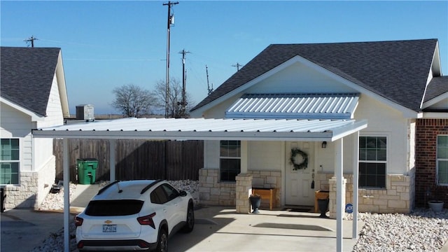 view of front of home with a carport, a shingled roof, and stone siding