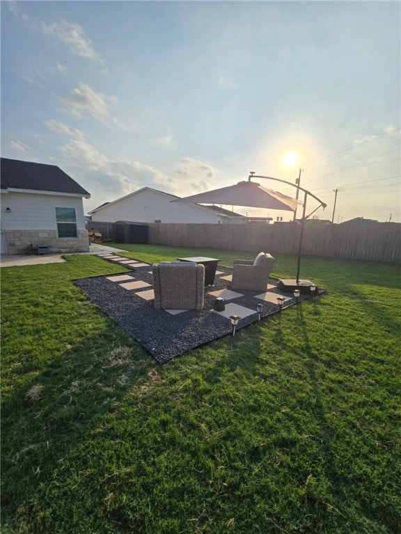 yard at dusk featuring a patio area, a fenced backyard, and an outdoor living space