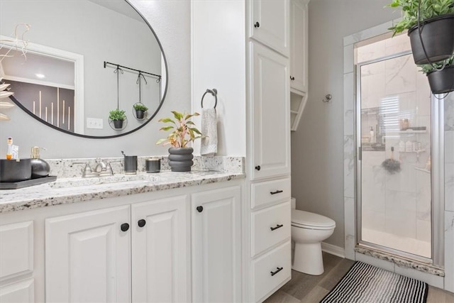 full bath featuring toilet, a stall shower, wood finished floors, and vanity