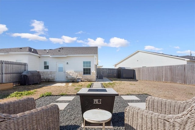 back of property featuring a patio area, stone siding, a fenced backyard, and a fire pit