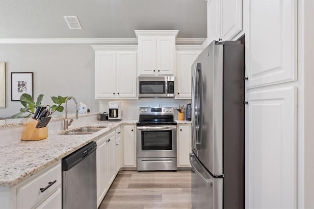 kitchen featuring ornamental molding, appliances with stainless steel finishes, a sink, and white cabinets