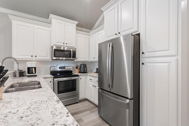 kitchen with appliances with stainless steel finishes, a sink, light stone counters, and white cabinets