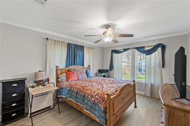 bedroom with crown molding, a textured ceiling, visible vents, and light wood-style floors