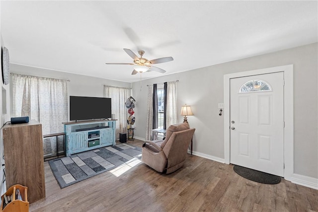 living room with ceiling fan, baseboards, and wood finished floors