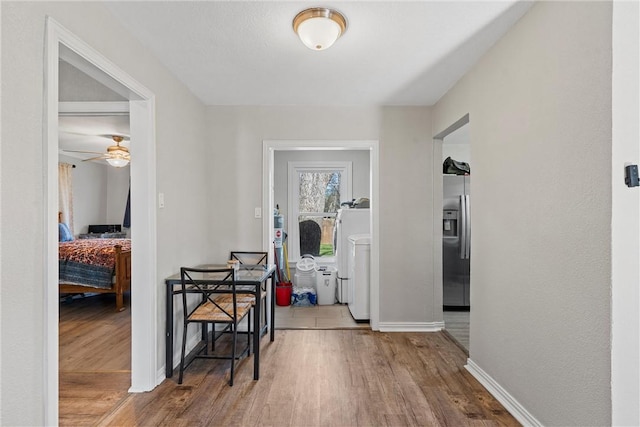 hall with washer / dryer, baseboards, and wood finished floors