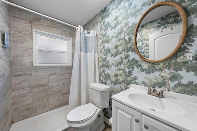 full bath with a tile shower, vanity, toilet, and wallpapered walls