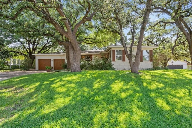 single story home with a front lawn, a garage, brick siding, and driveway