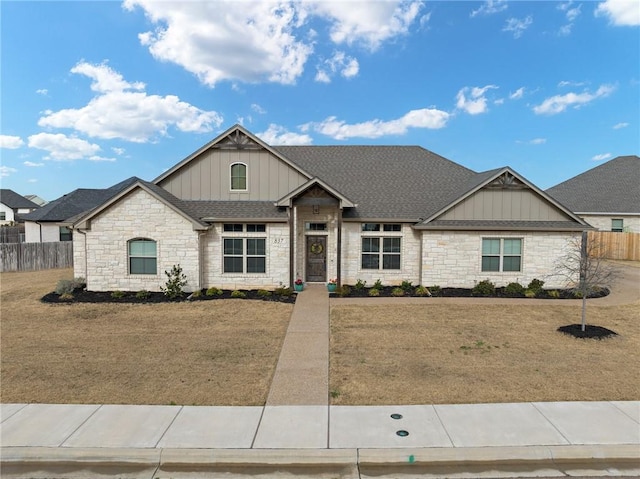 view of front of home featuring a front yard, fence, board and batten siding, and roof with shingles