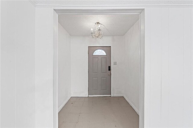 doorway to outside with wood walls, a textured ceiling, and a chandelier