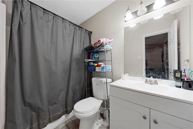 bathroom with hardwood / wood-style floors, vanity, a textured ceiling, and toilet