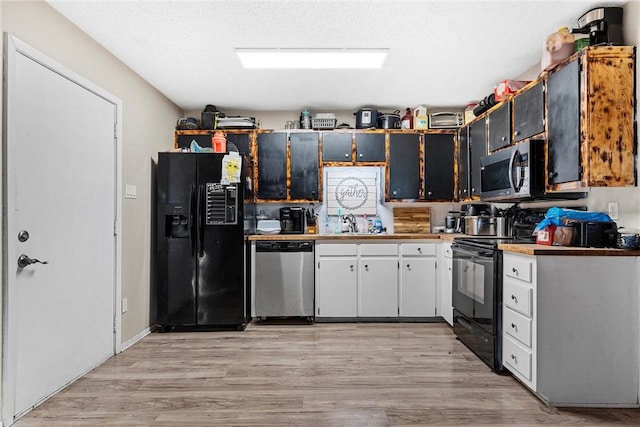 kitchen featuring a textured ceiling, light hardwood / wood-style flooring, and black appliances