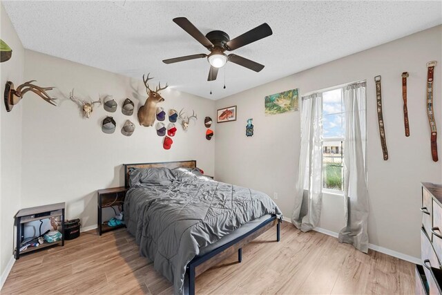 bedroom featuring ceiling fan, light wood-type flooring, and a textured ceiling