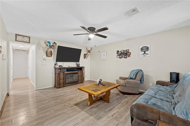 living room with ceiling fan, a textured ceiling, and hardwood / wood-style flooring