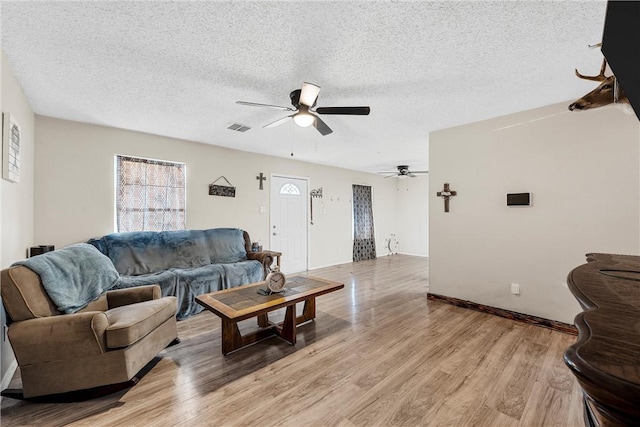 living room featuring ceiling fan, a textured ceiling, and light hardwood / wood-style flooring