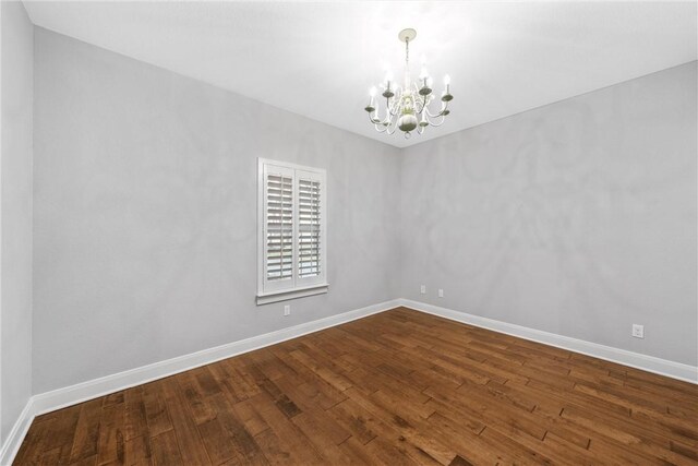 unfurnished room with wood-type flooring and an inviting chandelier