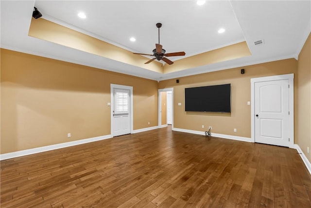 unfurnished living room featuring hardwood / wood-style floors, a tray ceiling, ceiling fan, and ornamental molding