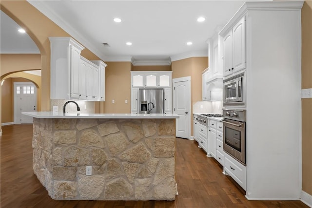 kitchen with appliances with stainless steel finishes, tasteful backsplash, dark wood-type flooring, sink, and white cabinetry