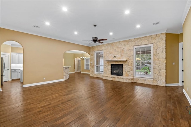 unfurnished living room featuring a stone fireplace, ceiling fan, dark hardwood / wood-style floors, and ornamental molding