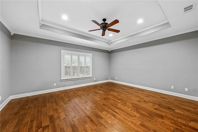 unfurnished room featuring hardwood / wood-style flooring, ceiling fan, ornamental molding, and a tray ceiling