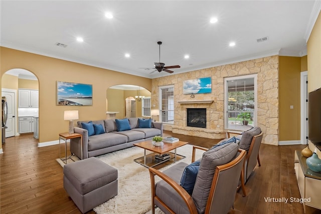 living room with a fireplace, ceiling fan with notable chandelier, dark hardwood / wood-style floors, and ornamental molding