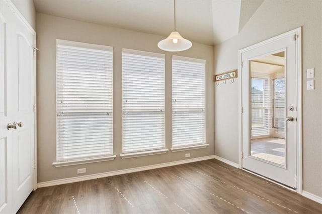 unfurnished dining area featuring a wealth of natural light, baseboards, and wood finished floors