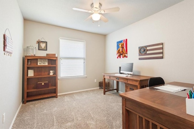 office space with a ceiling fan, light colored carpet, and baseboards