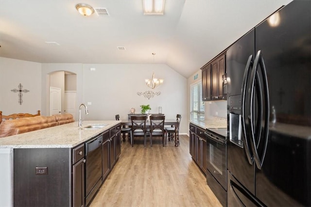 kitchen featuring lofted ceiling, a sink, visible vents, light wood-type flooring, and black appliances