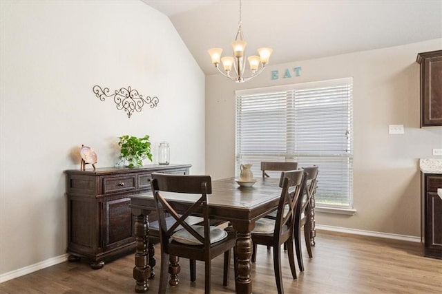 dining area with lofted ceiling, an inviting chandelier, baseboards, and wood finished floors