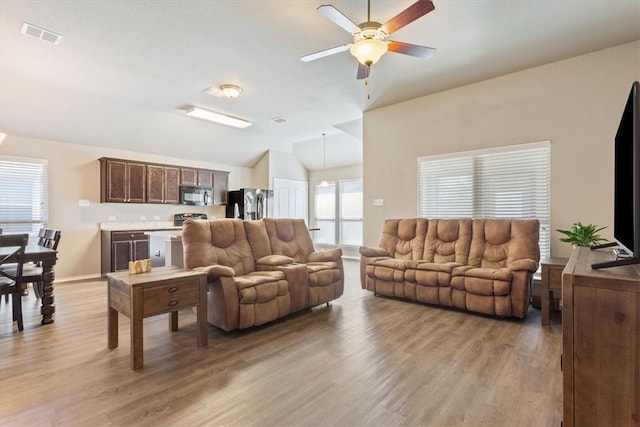 living area featuring vaulted ceiling, ceiling fan, light wood finished floors, and visible vents