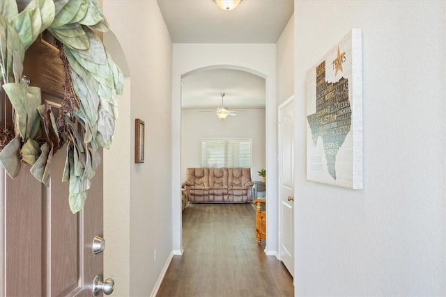 hall with arched walkways, wood finished floors, and baseboards