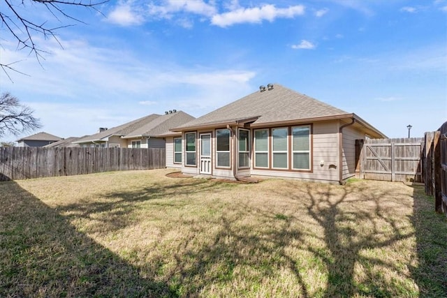 rear view of house featuring a fenced backyard, a lawn, and roof with shingles