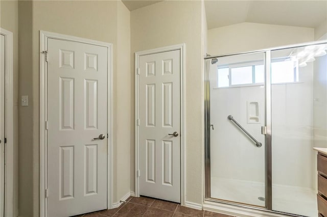 bathroom with tile patterned flooring, vanity, vaulted ceiling, and a shower with shower door