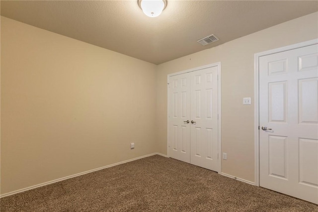 unfurnished bedroom featuring dark carpet and a closet