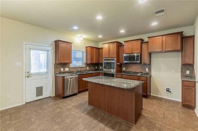 kitchen featuring dark stone counters, a center island, stainless steel appliances, and sink