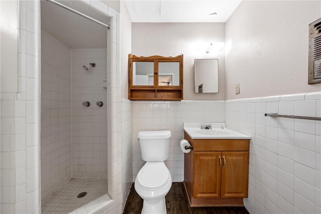 bathroom featuring toilet, tiled shower, hardwood / wood-style floors, tile walls, and vanity