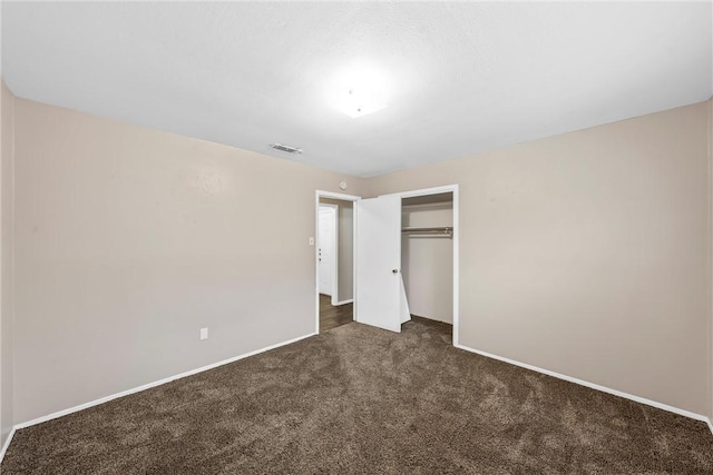 unfurnished bedroom featuring a closet and dark colored carpet