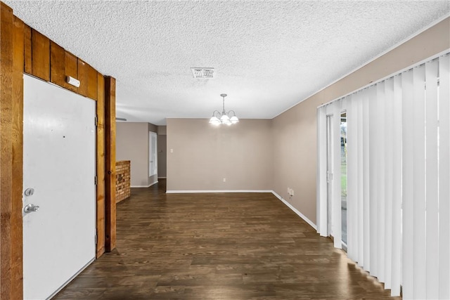 interior space featuring dark hardwood / wood-style flooring, a textured ceiling, and a chandelier