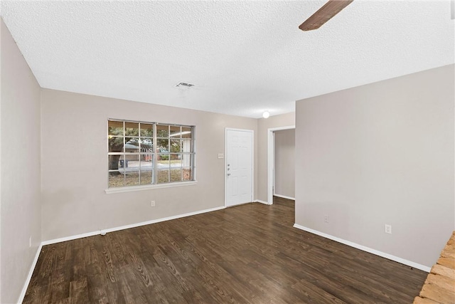 spare room with a textured ceiling and dark hardwood / wood-style floors