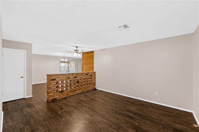 unfurnished living room featuring a textured ceiling, an inviting chandelier, and dark hardwood / wood-style floors