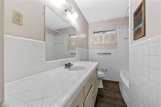 full bathroom featuring toilet, hardwood / wood-style flooring, tile walls, shower / bath combination, and vanity