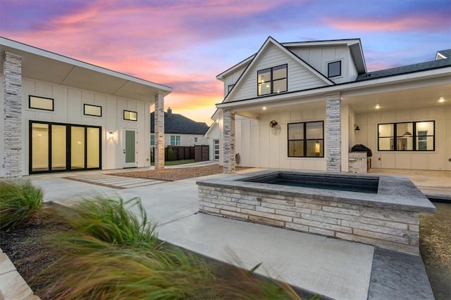 back house at dusk with an outdoor hot tub and a patio area