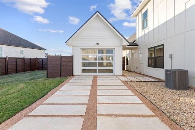 view of exterior entry with central AC unit, a patio, and a lawn