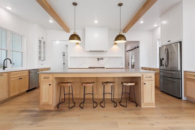 kitchen featuring beamed ceiling, a kitchen island, and stainless steel appliances