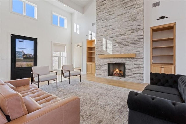 living room featuring a fireplace, a high ceiling, hardwood / wood-style flooring, and built in shelves