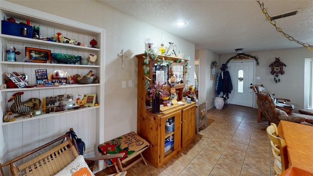 hall featuring light tile patterned flooring and a textured ceiling